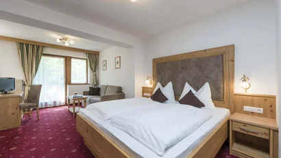 Gemütliches Hotelzimmer mit Doppelbett, Sofa und Fernseher