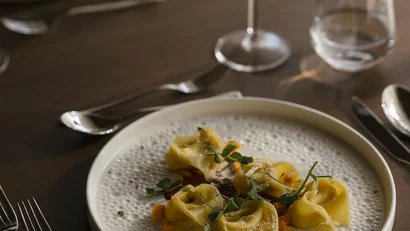 Teller mit Tortellini und einem Glas Rotwein auf dem Tisch