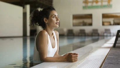 Woman relaxing at the edge of an indoor swimming pool