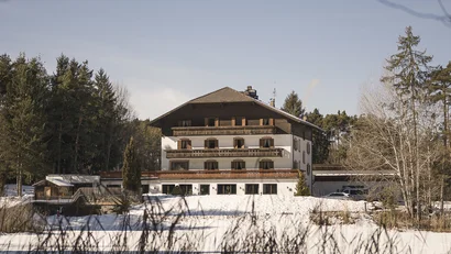 Großes Haus im Schnee umgeben von Bäumen unter klarem Himmel