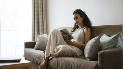 Woman reading relaxed on a sofa with cushions in a bright room