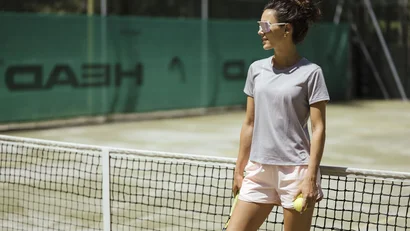 Woman holding tennis racket and ball standing on tennis court