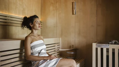 Woman relaxing in sauna wrapped in towel