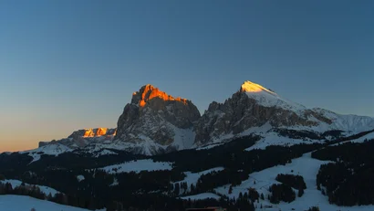 Schneebedeckte Berge im Abendlicht mit oranger Bus-Silhouette im Vordergrund