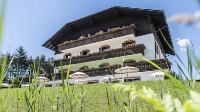 Traditionelles Alpenhaus mit Holzbalkonen und Blumen vor blauen Himmel