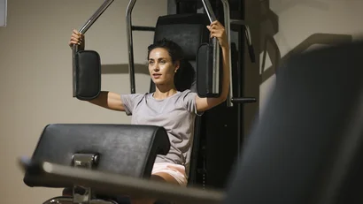Woman exercising on strength training machine in gym