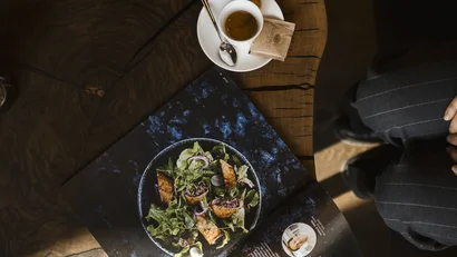 Tasse Espresso neben einem Magazin mit einem Salatfoto auf einem Holztisch