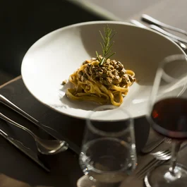 Pasta mit Fleischsauce garniert mit Rosmarin auf weißem Teller