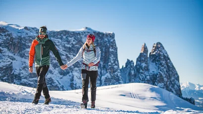 Paar wandert im Winter in den verschneiten Bergen bei klarem Himmel