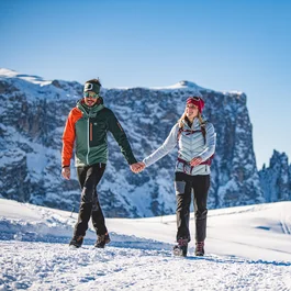 Paar wandert im Winter in den verschneiten Bergen bei klarem Himmel