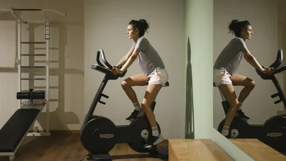 Woman exercising on a stationary bike in a gym room with mirror