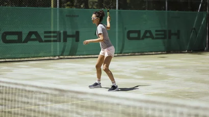 Woman playing tennis on outdoor court holding a tennis racket