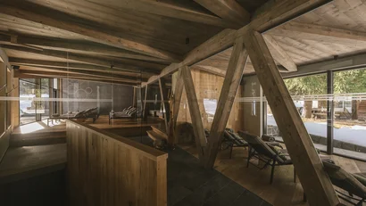 Moderner Ruheraum mit Holzdesign und Liegen mit Blick auf verschneite Landschaft