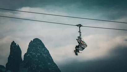 Sessellift mit Skifahrer vor bewölktem Berggipfel