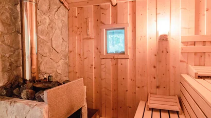 Innenansicht einer traditionellen Sauna mit Holzverkleidung und Steinofen