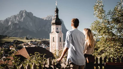 Paar betrachtet Kirche und Berglandschaft bei sonnigem Wetter