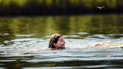 Ein Mädchen schwimmt in einem See mit einer Libelle darüber