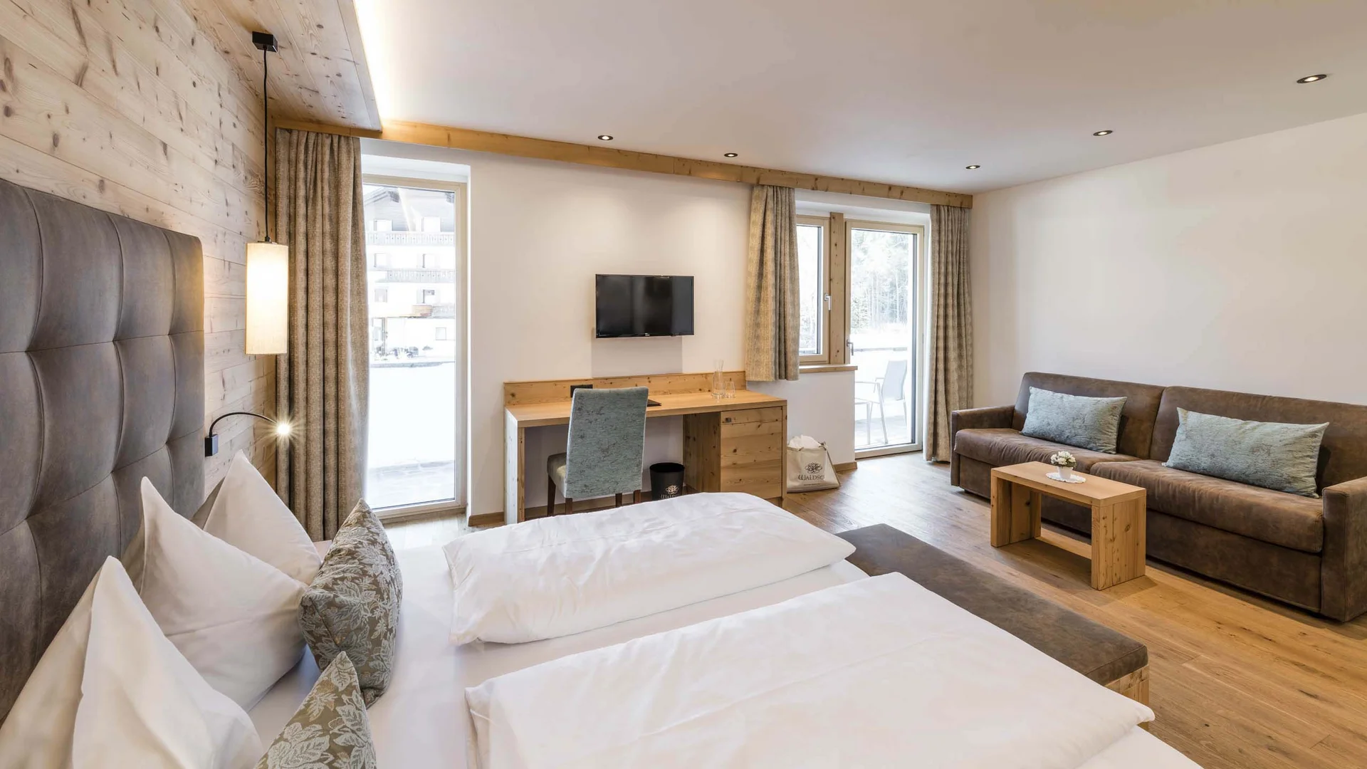 Modernes, helles Hotelzimmer mit Bett, Sofa und Schreibtisch