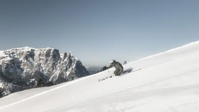 Skifahrer fährt auf verschneiter Berghang mit Bergen im Hintergrund