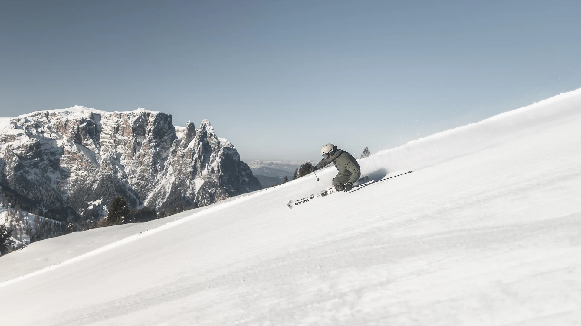 Skier skiing down snowy slope with mountains in background