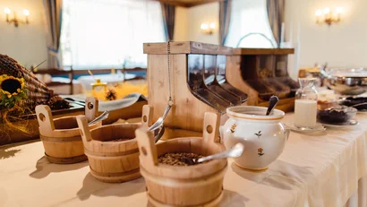 Holzbehälter mit Müsli und Milch in einem rustikalen Frühstücksbuffet