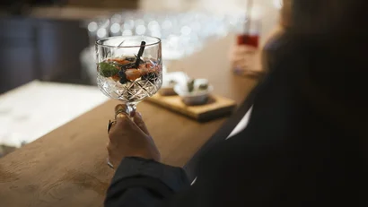Person holding a cocktail glass at a bar counter