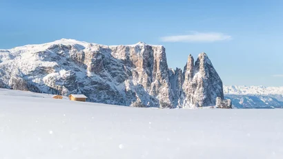 Schneebedeckte Berge mit kleinen Hütten unter klarem blauem Himmel