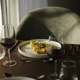 Teller mit Pasta und Gläser Rotwein auf einem gedeckten Tisch