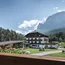 Hotel vor Bergkulisse mit Garten und blühenden Blumen im Vordergrund
