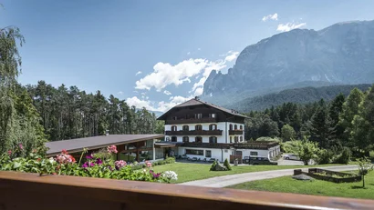 Hotel vor Bergkulisse mit Garten und blühenden Blumen im Vordergrund