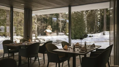 Gemütlicher Essbereich mit eingedeckten Tischen und Blick auf verschneite Landschaft