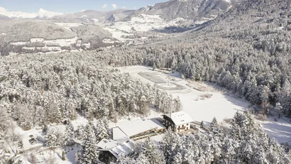 Schneebedeckte Wälder und Gebäude in einem Bergtal im Winter