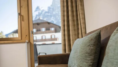 Braunes Sofa mit grünem Kissen und Fenster mit Bergblick im Hintergrund