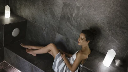 Woman relaxing in a modern steam room with gray tiles and soft lighting