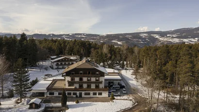 Hotel in verschneiter Berglandschaft umgeben von Wald und Bergen