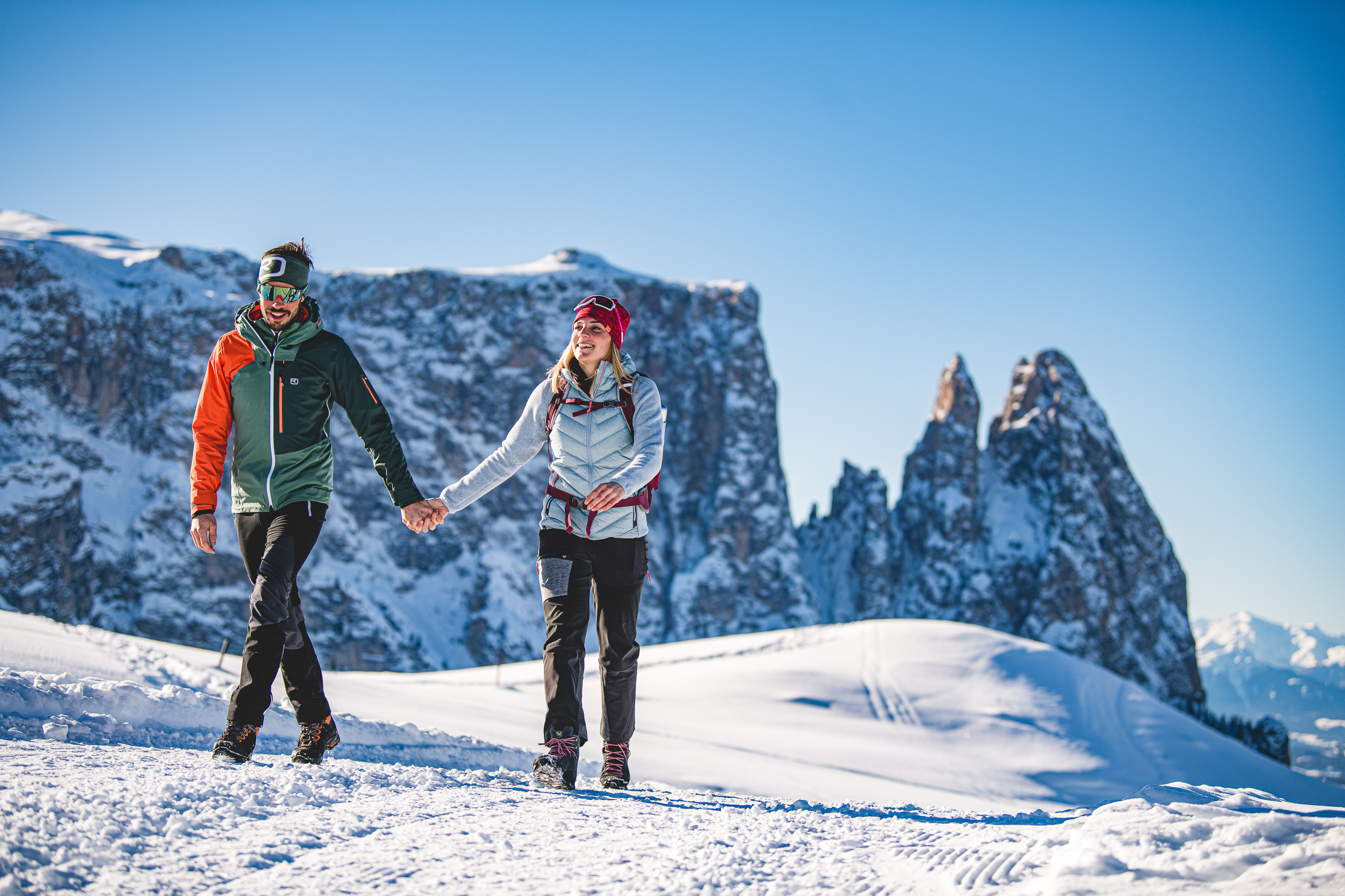 Couple walking in snowy mountains in winter under clear sky